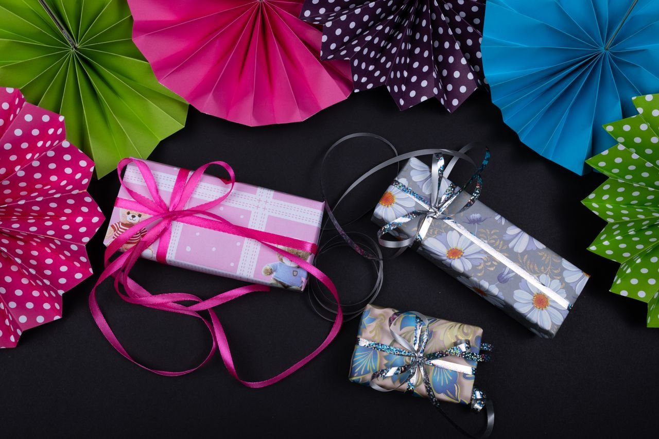 Vibrant gift boxes with ribbons amid colorful paper fans for festive occasions.